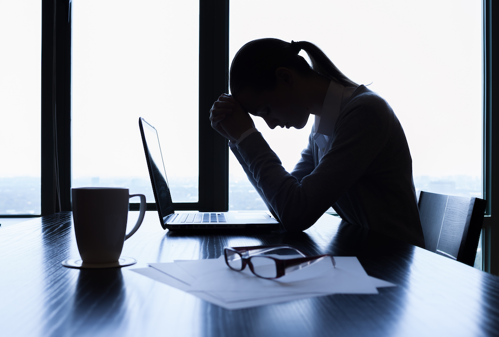 Stressed female employee sitting at desk